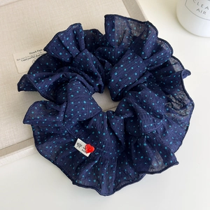 Close-up of oversized navy polka dot scrunchie with handmade label and heart charm