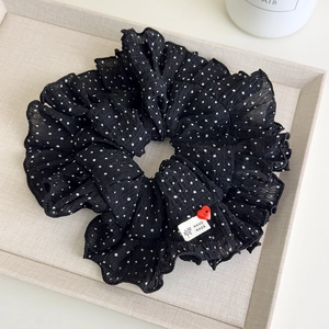 Close-up of black polka dot hair scrunchie with handmade label and red heart button detail