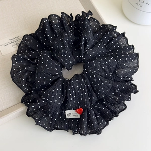 Macro detail of black polka dot scrunchie with red heart button and ruffles