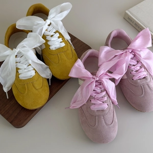 Stylish mustard and pink suede sneakers featuring large decorative satin ribbon bows