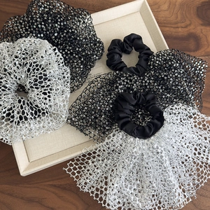 Elegant large sequin mesh scrunchies in black and silver on a light linen tray