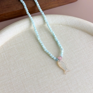 Vue macro d'un collier de perles bleu sarcelle avec pendentif poisson en nacre fine