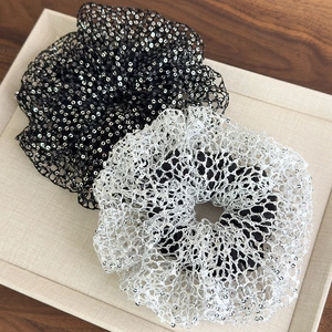 Close-up of black and silver sequined mesh scrunchies with elegant ruffled layers