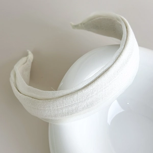Detail shot of a cream-white padded headband featuring soft bubble-textured fabric material