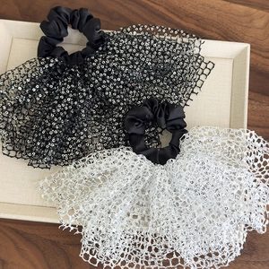 Close-up of sequin mesh scrunchies in black and white with elegant ruffled texture