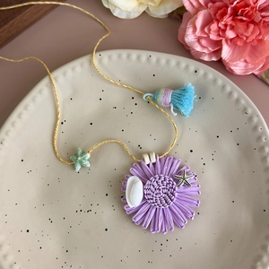 Détail d'un collier de fleurs tissées violettes avec coquillages et étoiles de mer