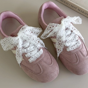 Detail von rosa Wildledersneakern mit eleganten weißen Schnürsenkeln aus Spitze
