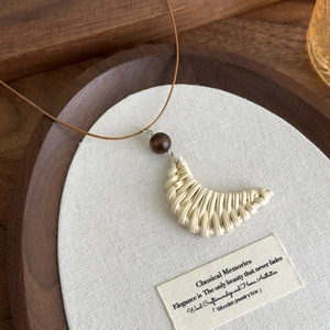 Macro detail of Bohemian crescent woven necklace with wooden bead and linen texture