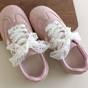 Nahaufnahme von rosa Wildlederschuhen mit eleganten weißen Spitzenbändern als Schleife