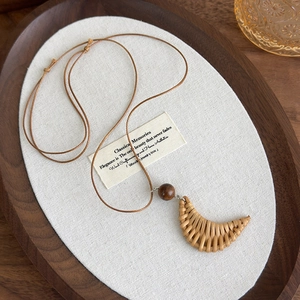 Detail of bohemian moon-shaped woven pendant on a vintage brown leather cord necklace