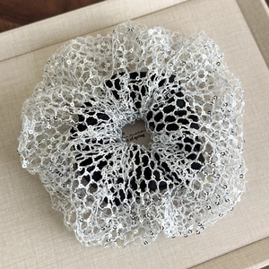 Detailed macro view of silver sequins and hollow mesh texture on a French style scrunchie