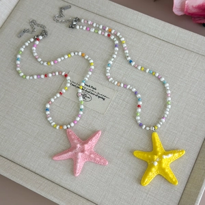 Close-up of colorful beaded necklace with large yellow starfish pendant on fabric texture
