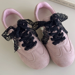 Detailansicht rosa Wildledersneaker mit breiten schwarzen Spitzenbandschleifen