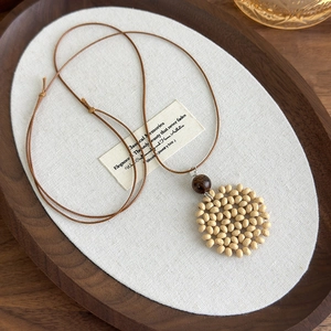 Detail of bohemian heart moon woven necklace with beige beads and brown cord
