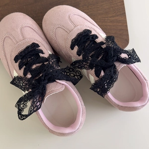Detailansicht der rosa Retro-Sneaker mit filigranen schwarzen Schnürsenkeln aus Spitze
