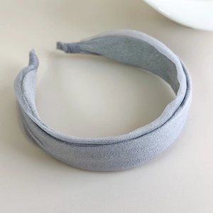 Detailed top view of wide light grey fabric headband on a minimalist beige background