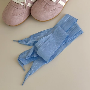 Close-up of wide sky blue organza ribbon shoelaces on pink sneakers for ballet core style