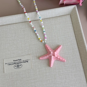 Detailed macro view of pink starfish pendant on colorful beaded summer vacation necklace