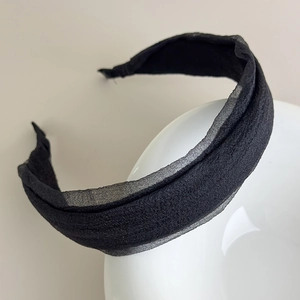 Detail view of the black gauze headband featuring pleated fabric on a white ceramic stand