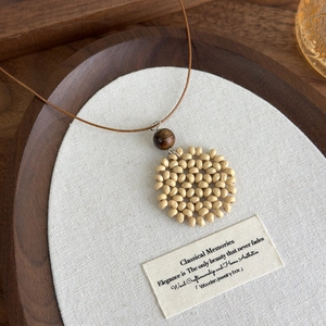 Detailed view of handcrafted bohemian wooden bead pendant with round woven design