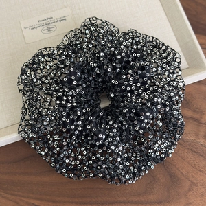 Detailed macro view of black mesh scrunchie featuring shimmering silver sequins