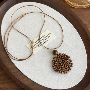 Close-up of Bohemian necklace showing handmade wooden beads and woven heart moon pendant