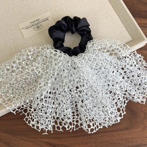 Close-up of black and white sequined scrunchie with lace ruffle detail on a tray