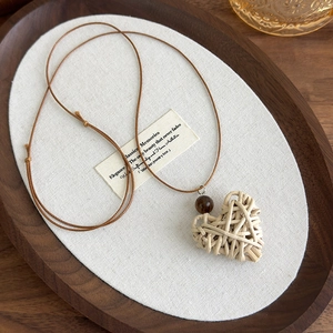 Close-up of heart-shaped woven pendant with wood bead on adjustable wax cord necklace