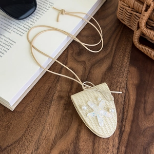 Détail du collier pochette étoile de mer tressé crème avec perles sur bois foncé