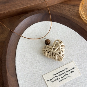 Detail of bohemian handmade heart-shaped woven pendant necklace with a wooden bead