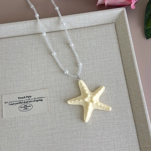 Detailed macro view of the cream starfish pendant with pearl beaded necklace on tray