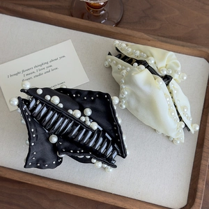 Detail of French style pearl claw clips in black and cream satin on a wooden tray