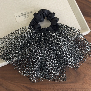 Close-up of black satin scrunchie with silver sequins and mesh skirt-like detail