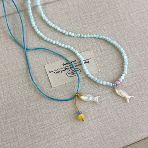 Detail der Perlenkette mit Fisch-Anhänger aus Perlmutt und geflochtener Kordeltextur