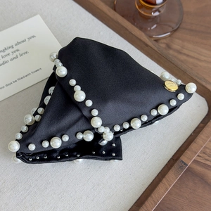 Detailed close-up of French satin shark hair clip with white pearls and gold metal label