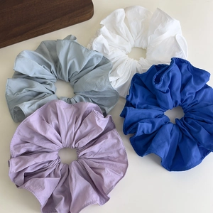 Detail of multi-colored ruffled fabric scrunchies in purple, blue, green, and white