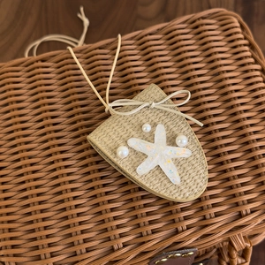 Détail du pendentif étoile de mer tressé avec perles blanches et nœud élégant