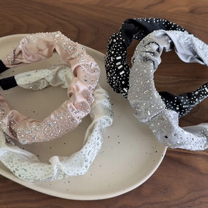 Dettaglio di cerchietti con nodo e strass in rosa, bianco, nero e grigio su piatto