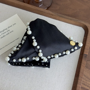 Detail of French silk bow hair claw with elegant pearls and a gold logo emblem