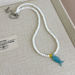 Detailaufnahme der Perlenkette mit Fisch-Anhänger und Muschelperlen in einer Schmuckschatulle