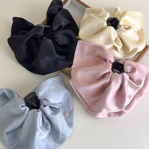 Detail of elegant satin bow hair claws in black, beige, pink and blue with gold buckles