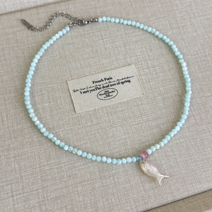 Detailansicht der hellblauen Perlenkette mit kleiner rosa Perle und Fisch-Muschelanhänger