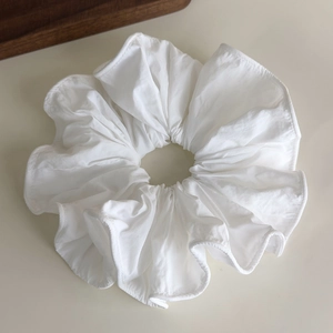Detail view of large white ruffled scrunchie with soft fabric and pleated edges