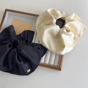 Detail of elegant black and beige satin hair claws with golden metal ornaments