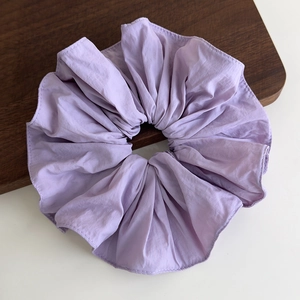 Detail of light purple ruffled fabric hair scrunchie showing pleated texture and stitching