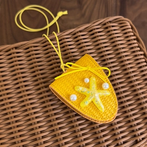 Détail du pendentif en paille jaune avec étoile de mer en résine et perles de plage