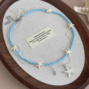 Blue starfish beaded double-layer necklace with Lucky tag on a wooden tray