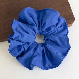 Detailed close-up of large blue ruffled scrunchie with fine stitching on a wooden tray