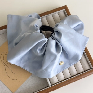 Macro view of light blue satin bow hair claw clip with elegant silk texture detail