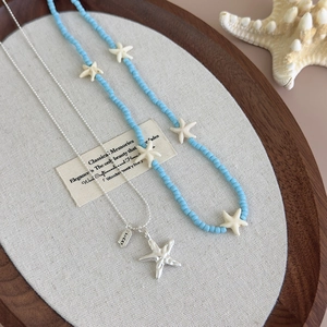 Macro shot of blue starfish beaded necklace and silver starfish pendant on wooden tray